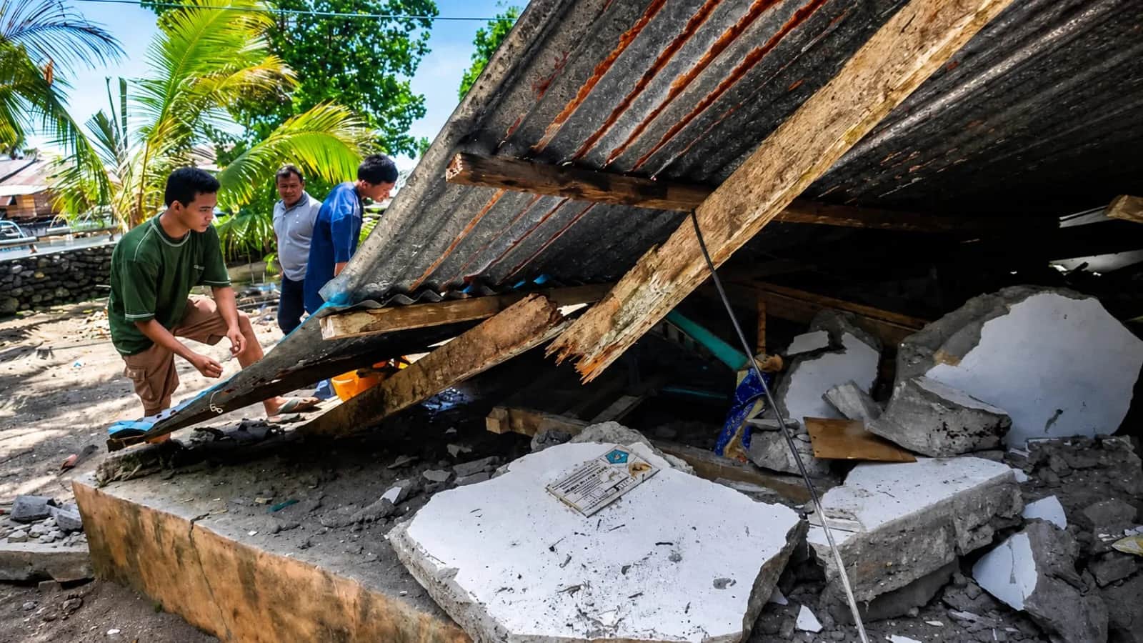 people inspect a damaged house after a powerful earthquake in the phillipines